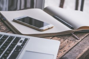 Smartphone next to a laptop and on a notebook.