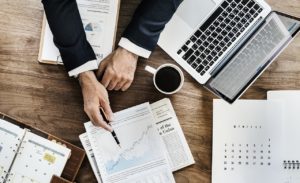 Businessman pointing to charts and results on table.
