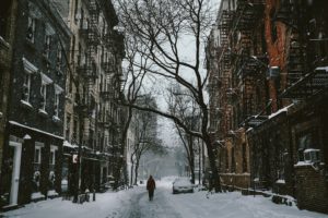Person walking down an empty snow-covered city street.
