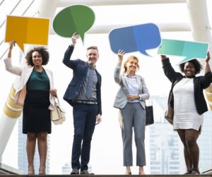 Different business people holding paper chat clouds and laughing.
