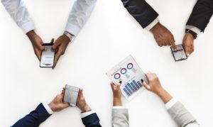 Four business people holding phones and a chart.