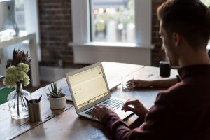 Man sitting as his desk, looking at a laptop.