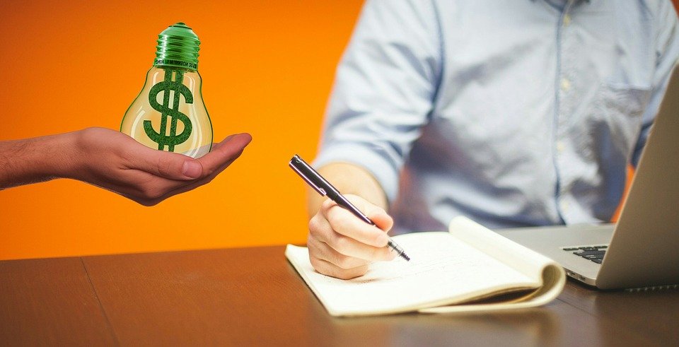 Person writing with $ lightbulb next to it.