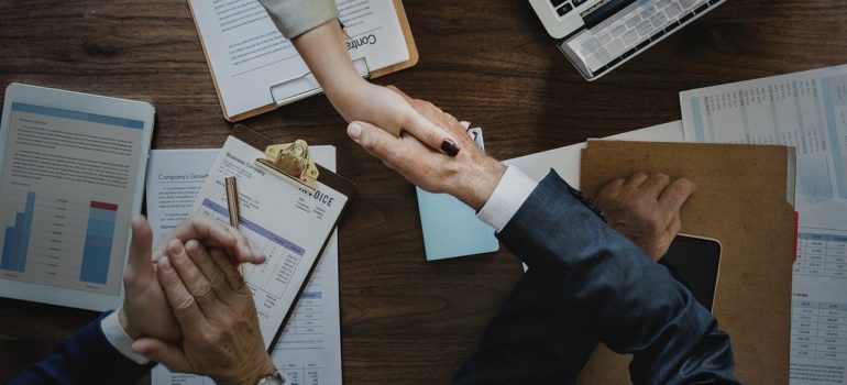 Handshake over a table with charts and contracts