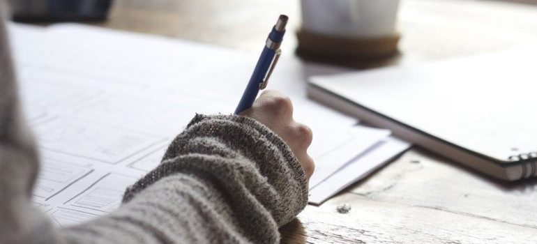 A girl writing on a piece of paper while considering outdoor advertising ideas for movers.