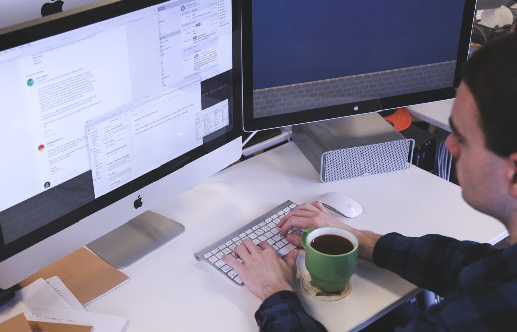 A person typing in front of two monitors
