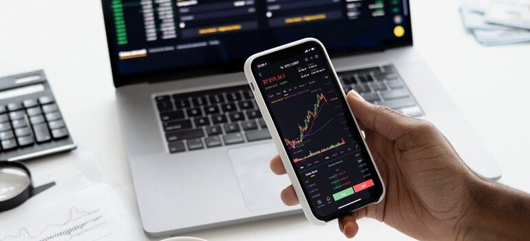 Person using a phone and laptop for finances.