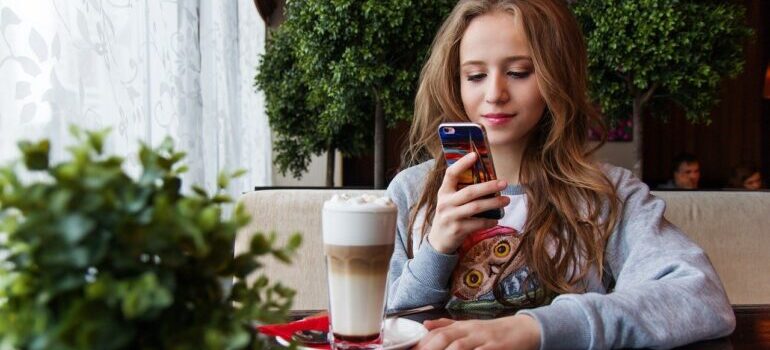 A woman sitting in a coffee shop and looking at her phone.