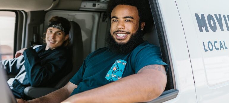 Two satisfied employees sitting in a moving van.