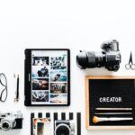Camera, tabltet, glasses, planning board and other tools needed to plan a marketing strategy.