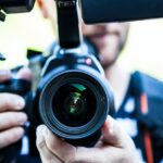 A guy holding a camer shooting vlogs for movers